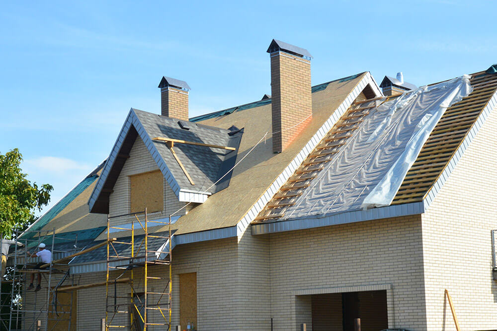 contractors laying a waterproofing membrane before laying asphalt shingles on a roof